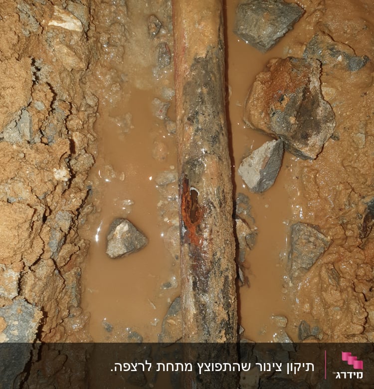 צינור חלוד עם נזילה באדמה רטובה